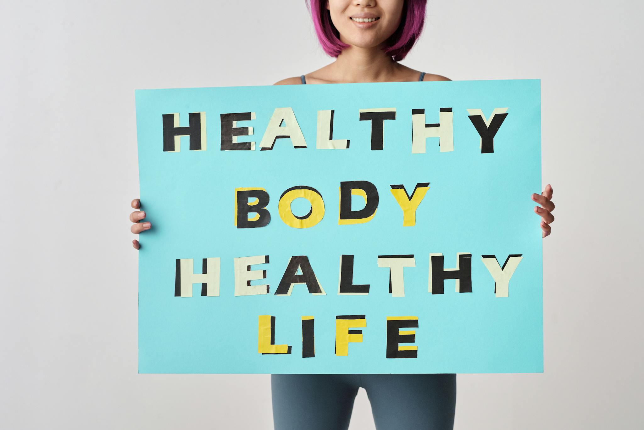 A woman holds a motivational poster advocating a healthy body and life for wellness.